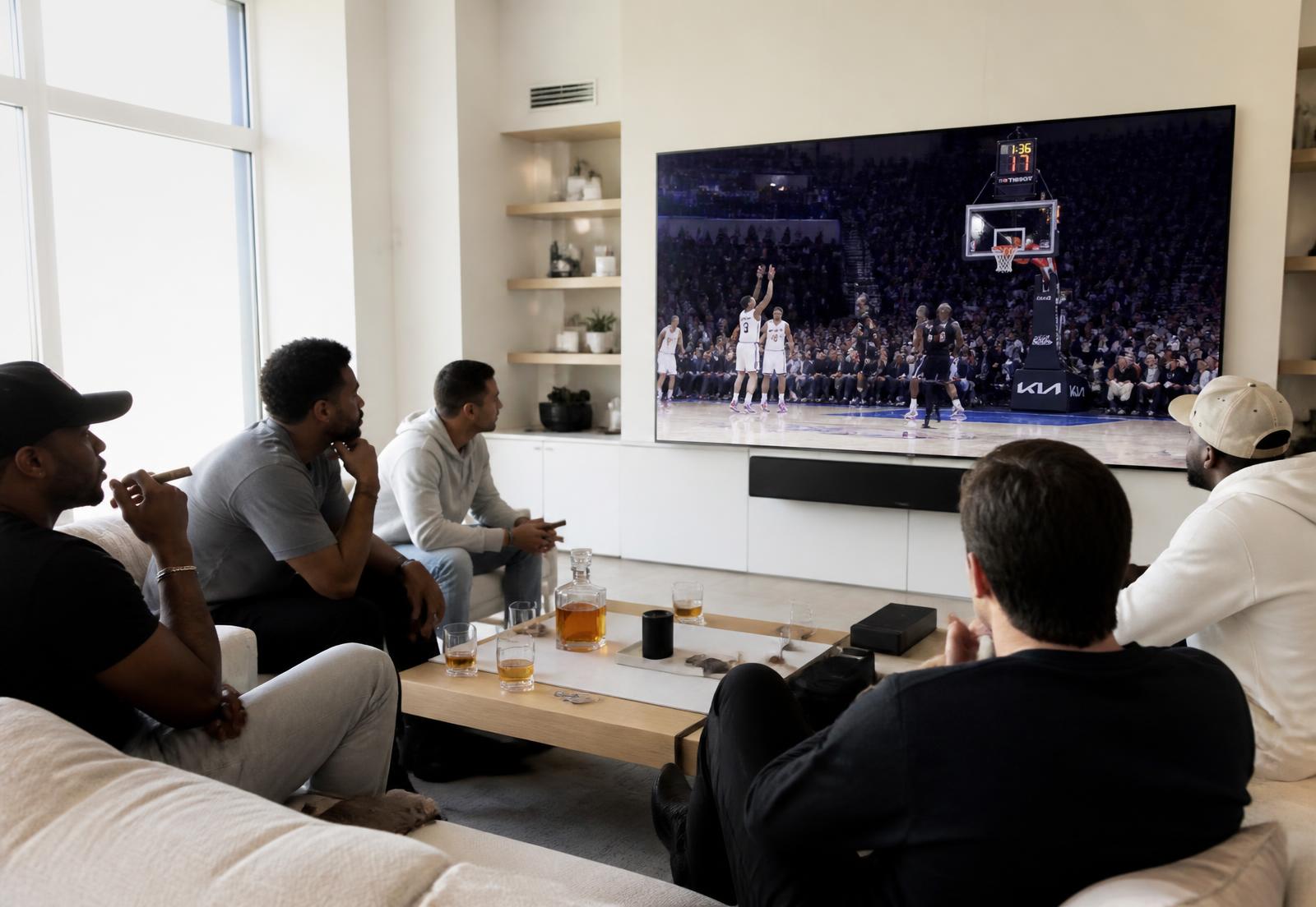 Guests on couches at Perfecto Lounge watching a basketball game on a large screen with cigars and drinks